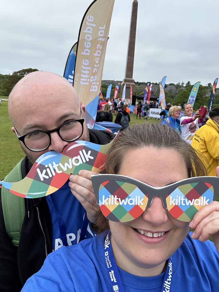 Two people with Kiltwalk photobooth props