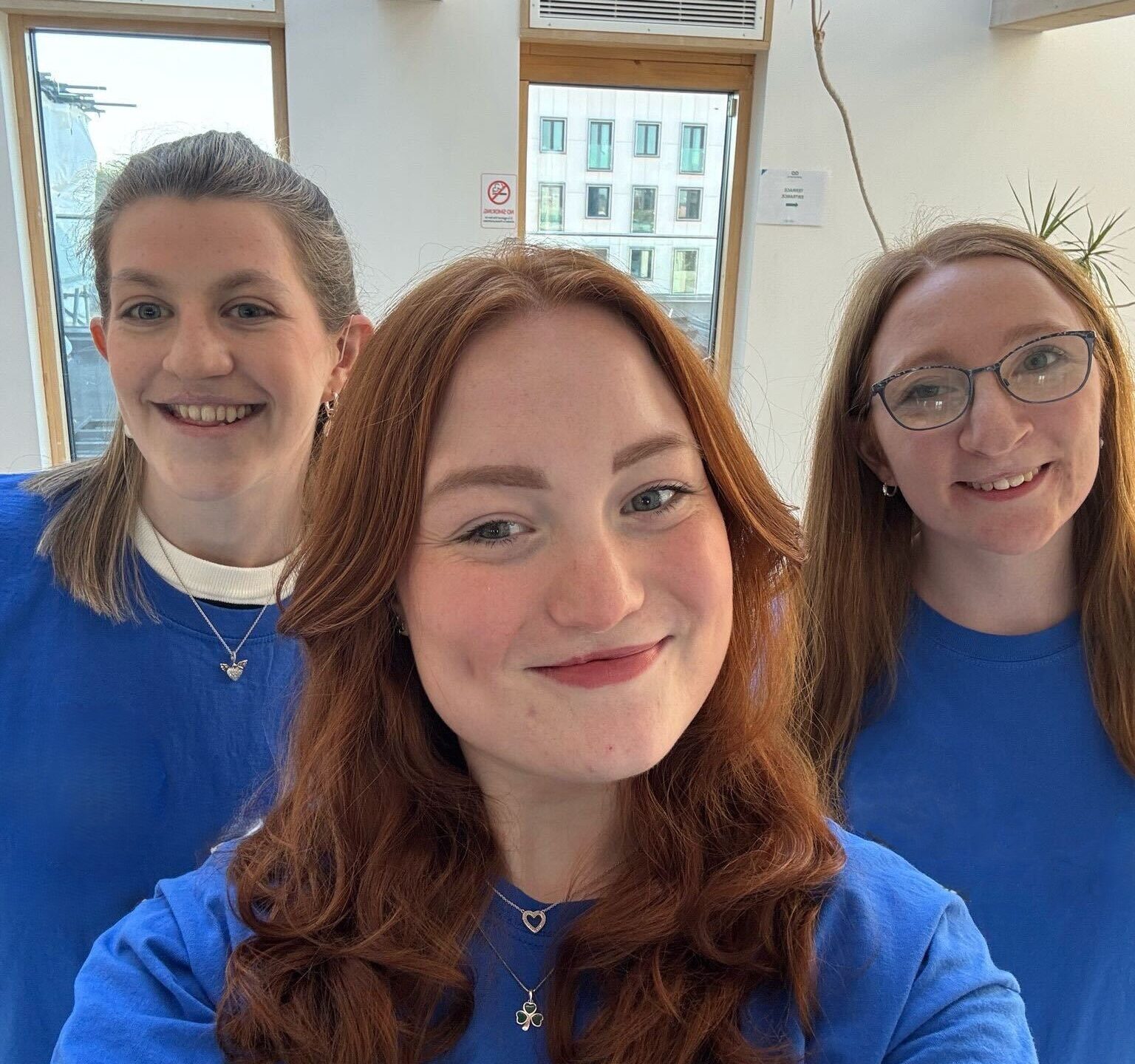 Three young CLAPA volunteers smile at the camera