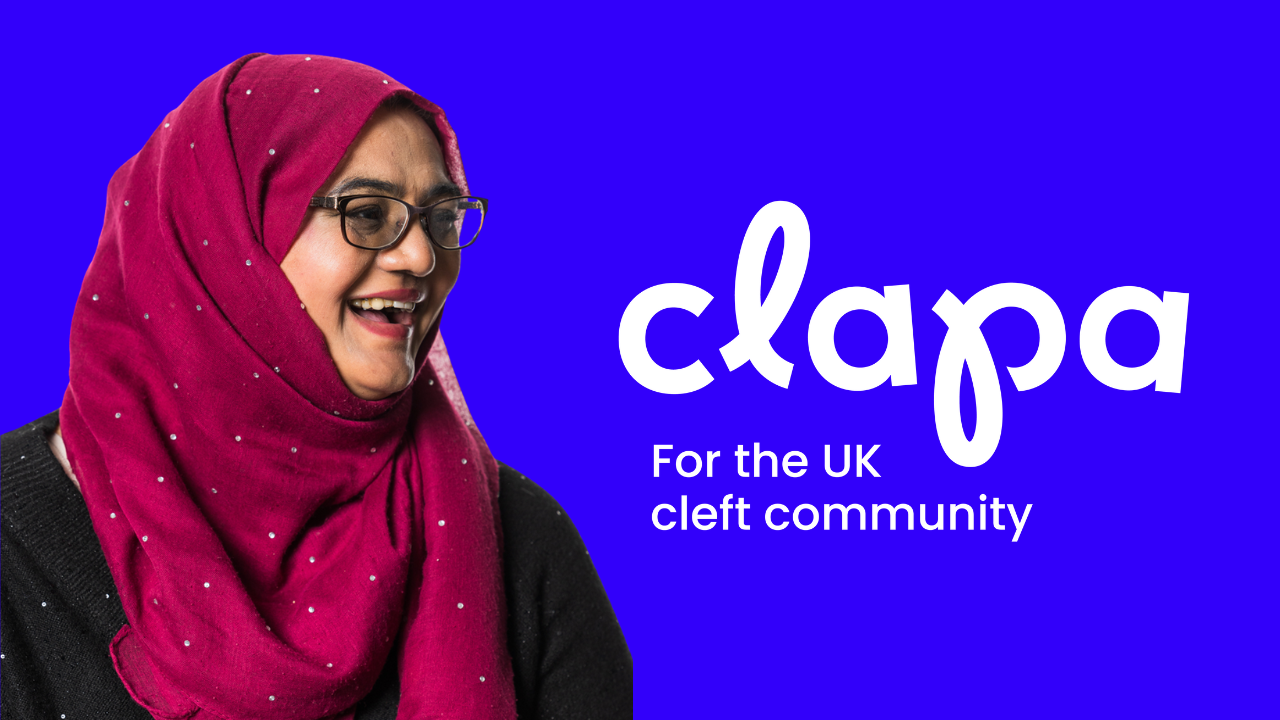 A lady is wearing a pink hijab and a black top. She is looking to the right and laughing. She has a repaired cleft. Next to her is the CLAPA logo with the strapline 'For the UK Cleft Community'
