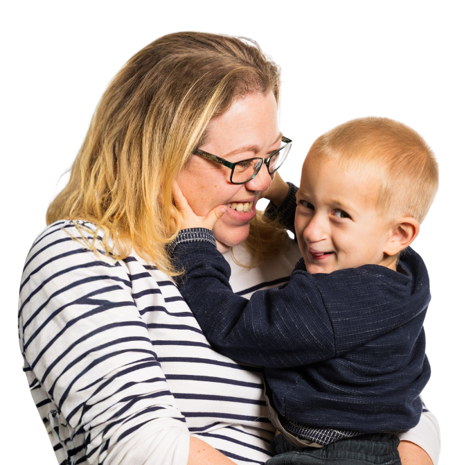 A blonde lady with glasses and her 5 year old blonde son. She is holding him and looking down laughing. The young son, Dylan, is holding her face and doing a cheeky look to camera. They both have repaired clefts.